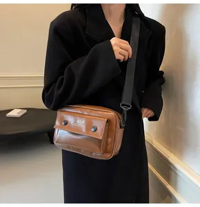 Bolso bandolera vintage de cuero marrón estilo cámara mostrado en una modelo con abrigo negro