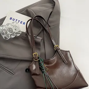 Detailed shot of a vintage brown glossy leather tote bag on a gray blazer background