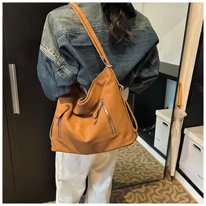 Détail d'un grand sac à bandoulière vintage en similicuir marron porté par une femme