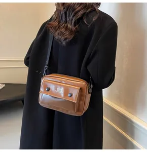 Detalle de un pequeño bolso bandolera cuadrado de cuero marrón vintage para mujer