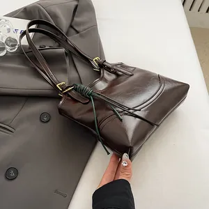 Close-up of vintage brown leather tote bag with unique green cord and gold buckles