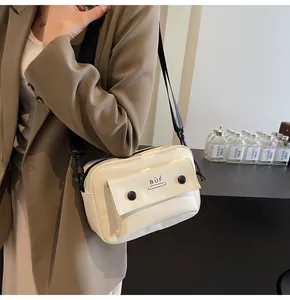 Bolso bandolera cuadrado blanco minimalista con detalle de bolsillo llevado por modelo