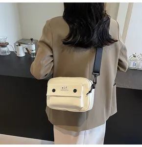 Bolso bandolera blanco minimalista para móvil lucido por una modelo en un café.