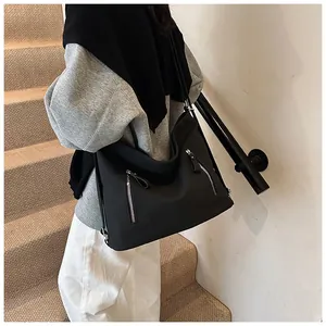 Vue détaillée d'un grand sac cabas noir minimaliste vintage porté à l'épaule