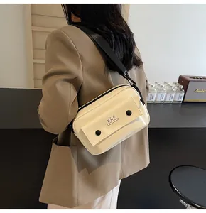 Vista detallada del bolso bandolera minimalista crema llevado por una modelo en una cafetería