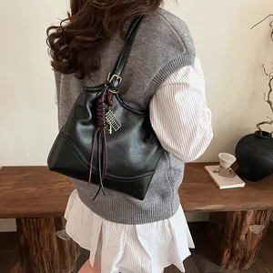 Vintage black bucket tote bag with red tassel accessory shown on model's shoulder