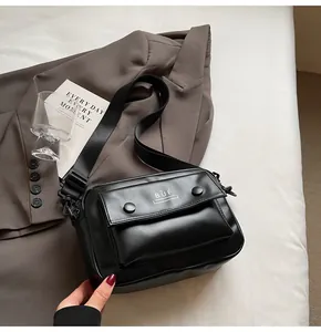 Primer plano de un bolso bandolera cuadrado negro minimalista con el logotipo de BUÉ