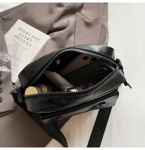 Vista interior del bolso bandolera negro minimalista que muestra la capacidad de almacenamiento
