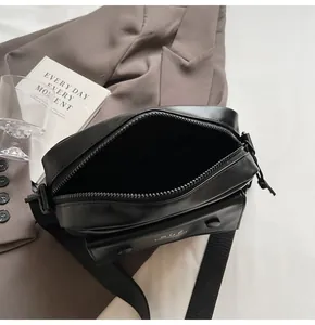 Detalle de cerca de un bolso bandolera negro abierto con forro interior espacioso