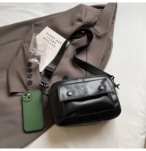 Primer plano de bolso mensajero retro negro con logo BÙF en el bolsillo delantero