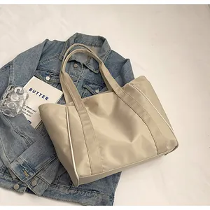 Detalle de un elegante bolso tote de nailon beige sobre una chaqueta vaquera azul