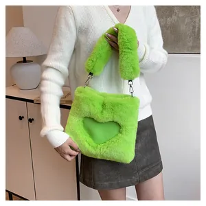 Primo piano di una borsa tote in peluche verde lime con cuore tenuta da una modella