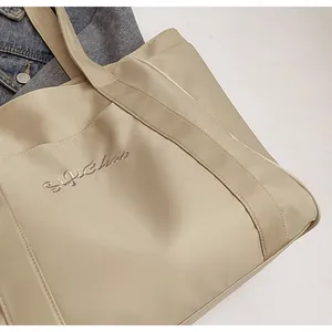 Primer plano detallado de un bolso tote de nailon beige premium con bordado elegante