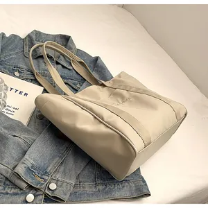Primer plano de un elegante bolso tote de nailon beige con detalle de logotipo bordado