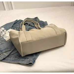Detalle de cerca de la base rectangular reforzada de este bolso de nailon beige
