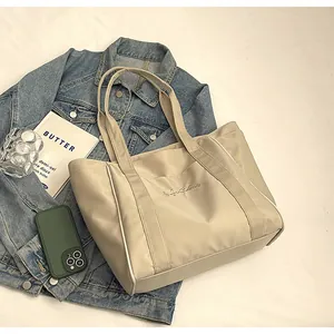 Primer plano de un elegante bolso tote de nailon beige sobre una chaqueta vaquera