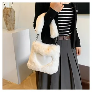 Dettaglio di una borsa tote bianca in ecopelliccia a cuore indossata da una modella.