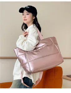 Close-up detail of large metallic pink puffer travel bag carried by a stylish model.