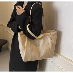 Elegante bolso tote de nailon beige para mujer usado por modelo con blazer negro