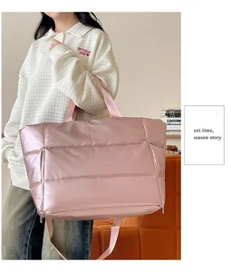 Close-up of a metallic pink quilted travel bag carried by a female model in an indoor setting