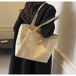 Elegante bolso tote de nailon beige con bordado llevado por una modelo para uso diario