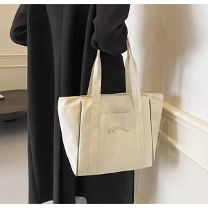 Vista detallada de un bolso tote de nailon blanco crema con el bordado SiJiChao