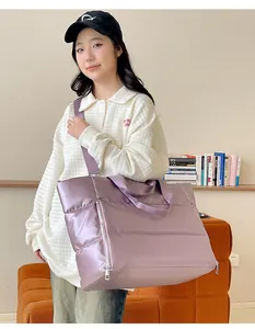 Asian woman carrying a large purple metallic puffer travel tote bag in a cozy indoor setting