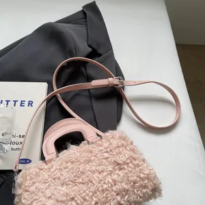 Close-up detail of a soft pink plush faux fur handbag with adjustable leather strap
