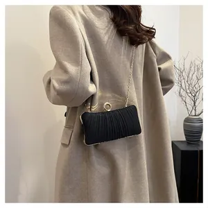 Elegant black pleated evening clutch bag with golden chain strap and ring clasp detail