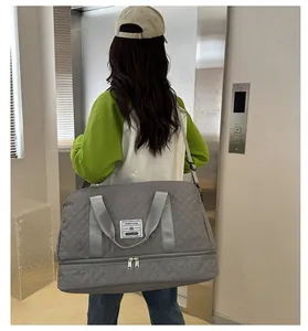 Rear view of model carrying a large gray quilted duffel bag in a modern hallway setting.