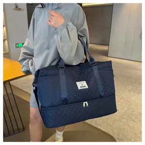 Large navy blue quilted travel duffel bag with shoe compartment held by a model