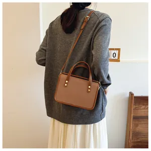 Vue arrière d'un mannequin portant un sac à main carré patchwork marron minimaliste