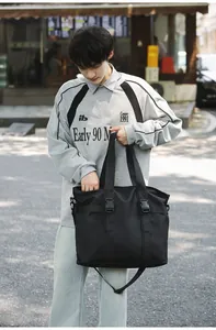 Asiatisches Model mit einer großen schwarzen multifunktionalen Reisetasche im Freien