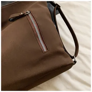 Gros plan d'un sac bandoulière en daim marron vintage avec une poche zippée argentée