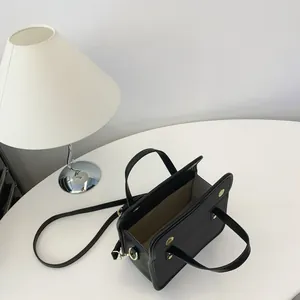 Vue de dessus d'un sac à main noir minimaliste montrant la doublure sur table blanche