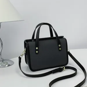 Vue détaillée d'un sac à main carré noir minimaliste avec panneau avant texturé