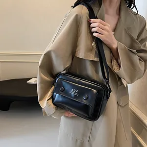 Bolso bandolera negro minimalista para mujer con un detalle de bolsillo frontal
