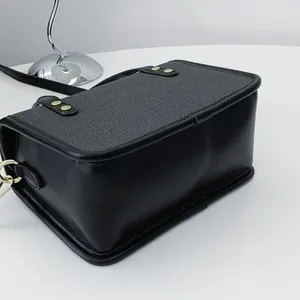 Gros plan sur le panneau texturé gris et le cuir noir d'un petit sac en forme de boîte