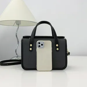 Vue détaillée du petit sac à main carré gris avec un smartphone pour référence de taille