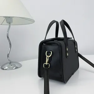 Vue détaillée d'un petit sac à main noir avec des finitions en métal doré brillant