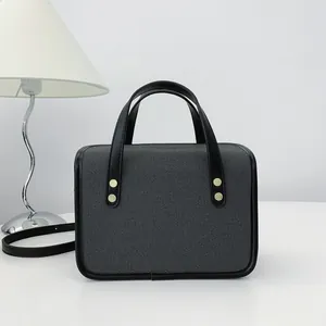 Vue détaillée d'un petit sac à main texturé gris minimaliste avec des poignées noires