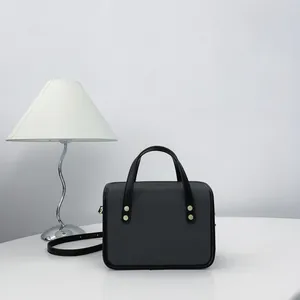Élégant sac à main carré noir minimaliste affiché à côté d'une lampe de bureau moderne