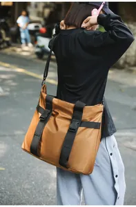 Modell mit einer großen braunen Nylon-Reisetasche mit schwarzen Schnallen im Freien