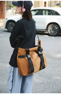 Detailansicht der großen braunen Reisetasche, die von einem Model im Freien getragen wird