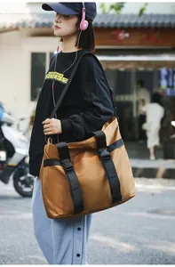 Detailansicht einer großen khakifarbenen Nylon-Reisetasche, die von einem Modell getragen wird