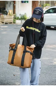 Asiatisches Model trägt eine große braune Outdoor-Reisetasche in einem Straßen-Szenario