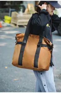 Lifestyle-Aufnahme einer großen braunen Reisetasche, die von einem Modell getragen wird.