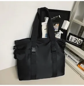 Große schwarze Nylon-Reisetasche mit Schnallenriemen in einer Lifestyle-Schreibtischumgebung