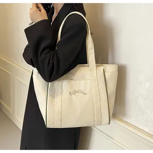 Detalle del bolso tote de nailon crema con bordado Siji Chao y ribete verde