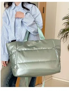 Detail shot of model carrying large mint green metallic puffer tote bag for travel and gym